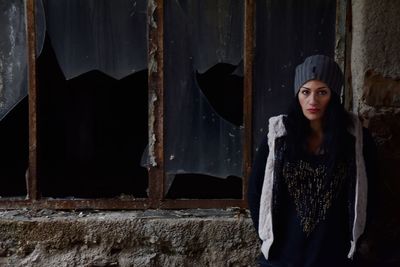 Woman standing against abandoned building