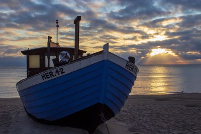 Ship moored on beach against sky during sunset