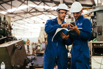 Low angle view of factory workers reading manual in factory