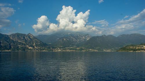 Scenic view of sea by mountains against sky