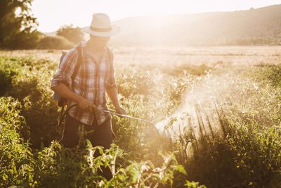 Man spraying pesticide on plants in farm