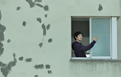 Portrait of serious young boy standing at wwindow