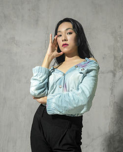 Portrait of young woman standing against wall