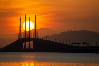 Scenic view of bridge over river against orange sky