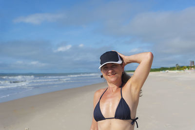 Portrait of young woman in bikini standing at beach