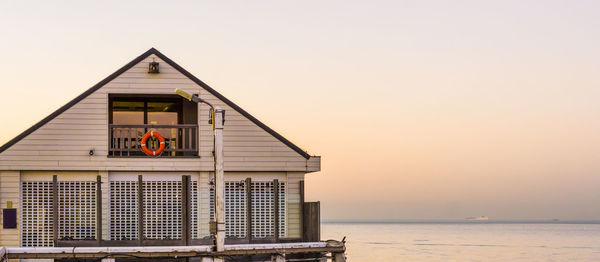 House by sea against sky during sunset