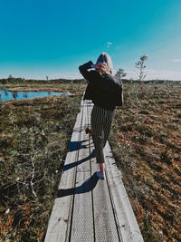 Rear view of woman standing on land against sky