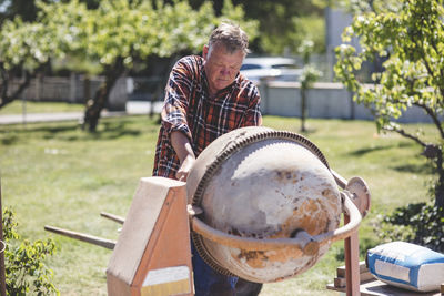 Senior man using cement mixer at yard