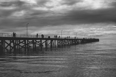 Pier over sea against sky, black and white