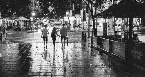 People walking on wet street at night