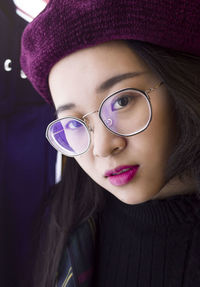 Close-up portrait of young woman wearing hat and eyeglasses