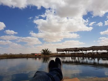 Low section of person in lake against sky