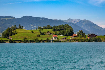 Scenic view of sea and mountains against clear blue sky