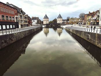 Bridge over river by buildings against sky in city