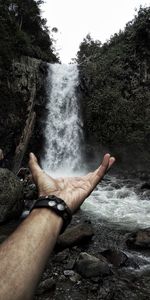 Midsection of man on rock against waterfall