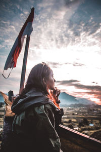 Woman holding umbrella against sky during sunset