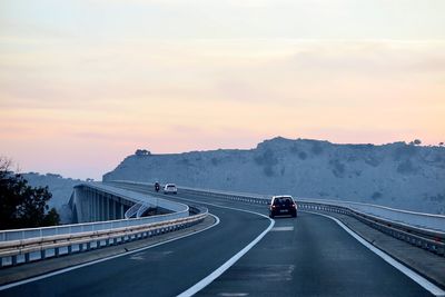 Cars on the bridge against sky during sunset