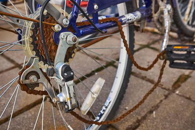 Blue bike has been outside all winter and got broken. rusty bicycle chain hangs on sprocket and gear