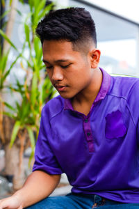 Young man looking away while sitting outdoors
