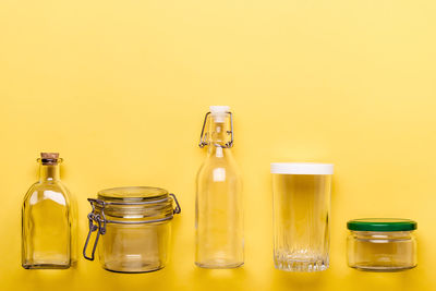 Close-up of various glass bottles against yellow background