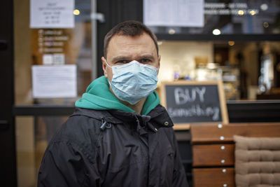 Portrait of man wearing mask standing in cafe