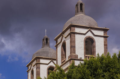 Low angle view of bell tower against cloudy sky