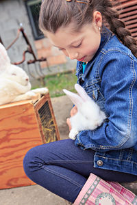 Cute girl holding rabbit outdoors