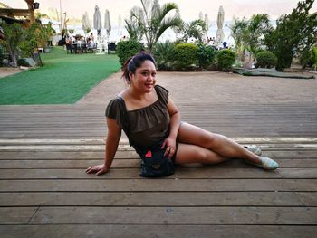 Young woman sitting on palm tree