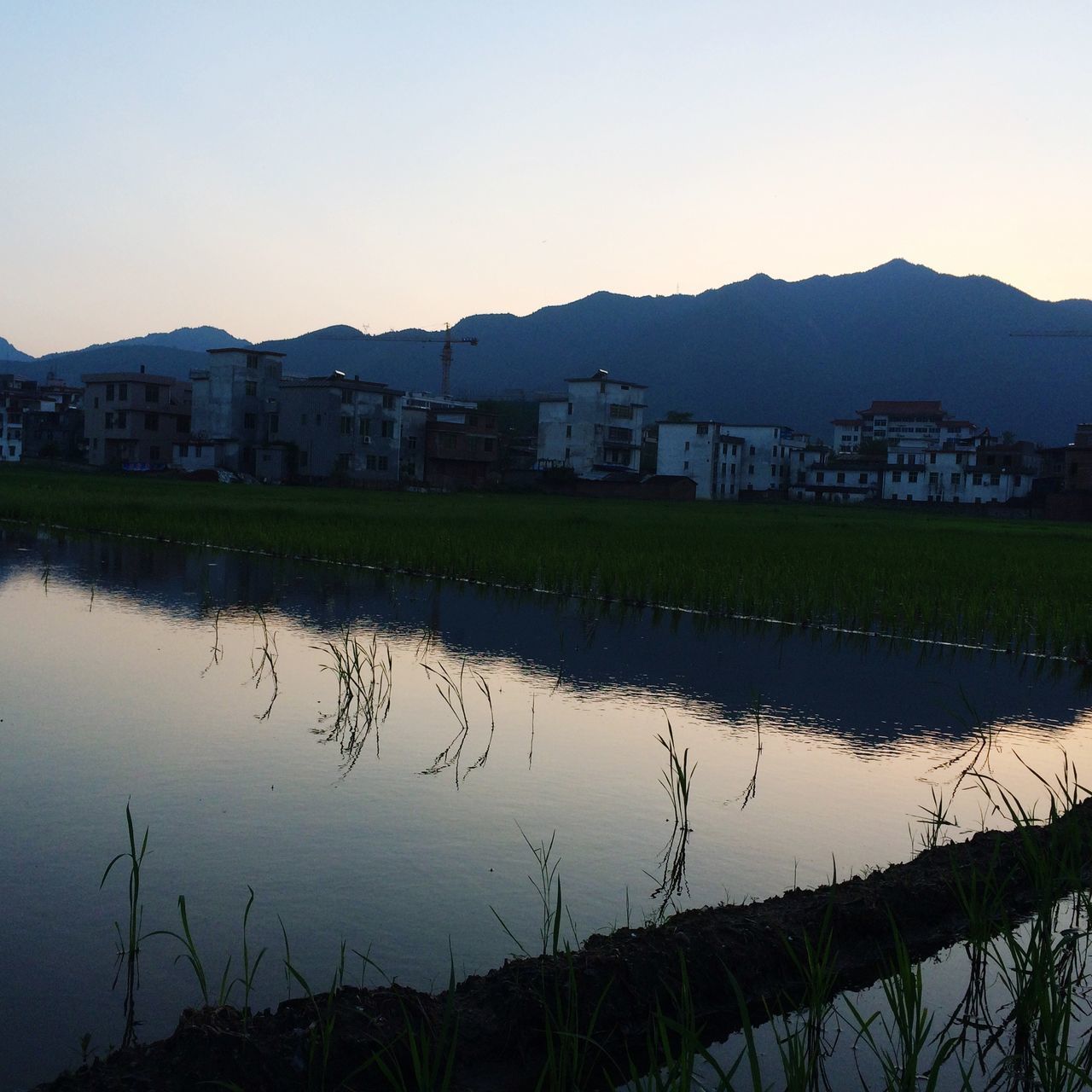 water, building exterior, built structure, architecture, clear sky, mountain, reflection, lake, river, copy space, tranquility, house, tranquil scene, nature, mountain range, beauty in nature, scenics, waterfront, standing water, residential structure