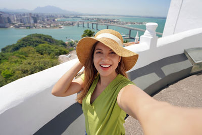 Tourist woman takes selfie with panoramic view of city of vitoria in espirito santo state, brazil