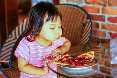 Cute girl blowing pizza slices at table