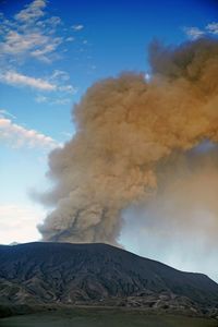 Smoke emitting from volcanic mountain against sky