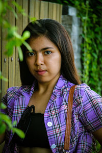 Portrait of beautiful young woman standing against plants