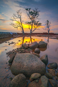 Rocks by sea against sky during sunset