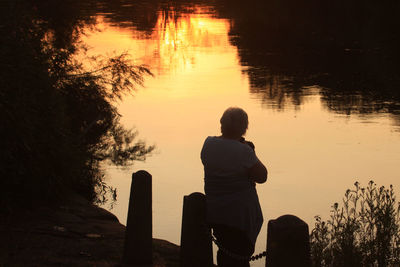 High angle view of woman standing by river during sunset