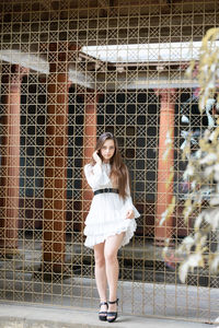 Portrait of a young woman standing against chainlink fence