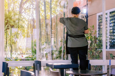 Rear view of man standing by window