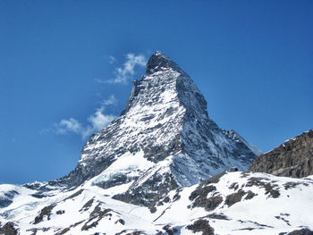 Low angle view of snowcapped mountain against blue sky