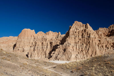 Panoramic view of rocky mountains against clear blue sky