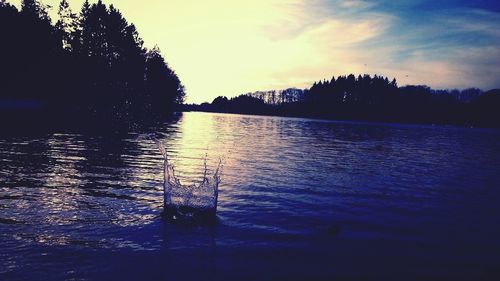 Reflection of trees in water at sunset