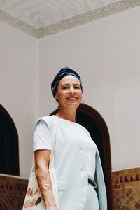 Portrait of young woman standing against wall