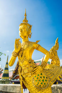 Low angle view of statue against temple building against sky