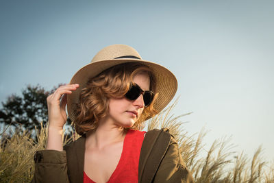 Low angle view of woman wearing hat and sunglasses against sky