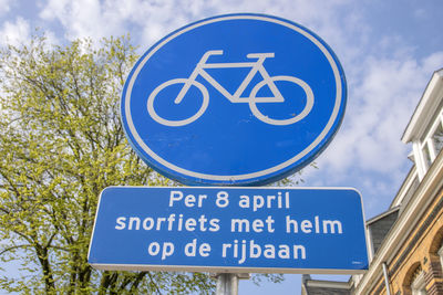 Low angle view of road sign against blue sky