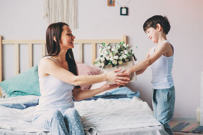 Mother and son holding flowers in box at home