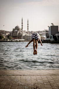 Rear view of woman jumping into river