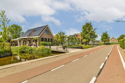 Empty road by building against sky