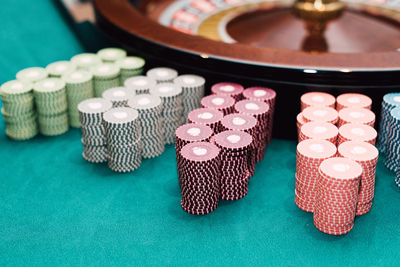 Close-up of casino chips stacked by roulette wheel on table