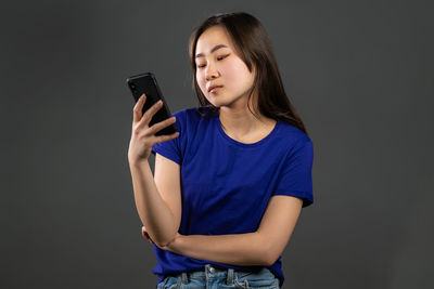 Low angle view of woman using mobile phone against black background