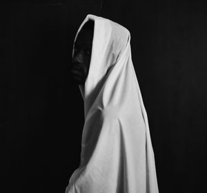 Close-up of person covering face against black background